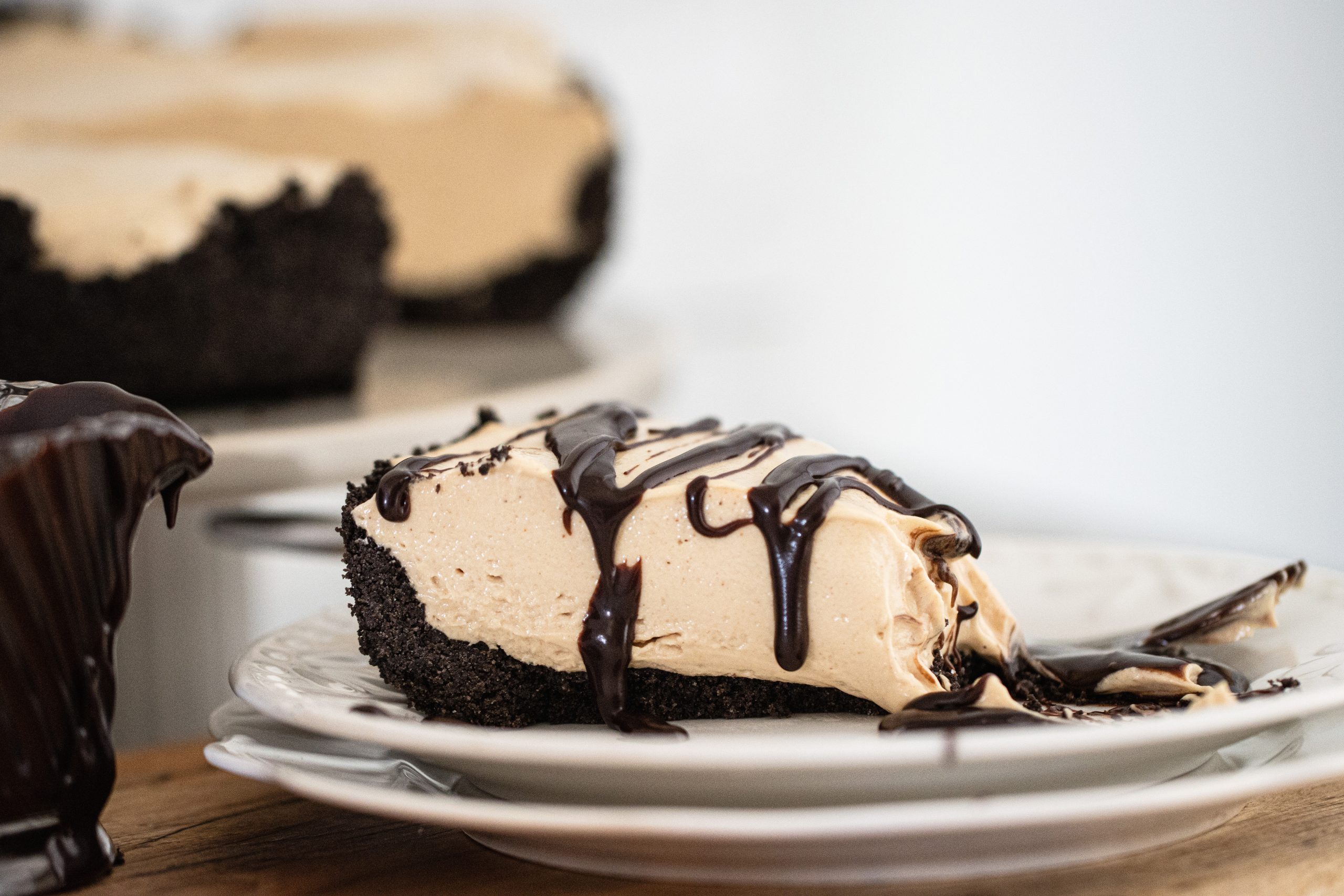 A no bake peanut butter pie on a saucer drizzled with chocolate sauce.